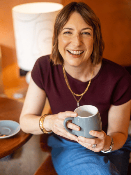 Zoe Jepson smiling and holding a mug of tea.